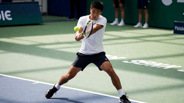 网球运动员在硬地赛场上挥拍击球的比赛瞬间